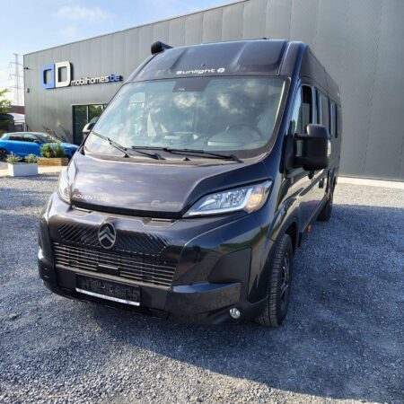 Front-left view of a dark gray camper van in a gravel lot, with 'Adventure' badge on the bonnet and 'Sunlight' on the windshield.